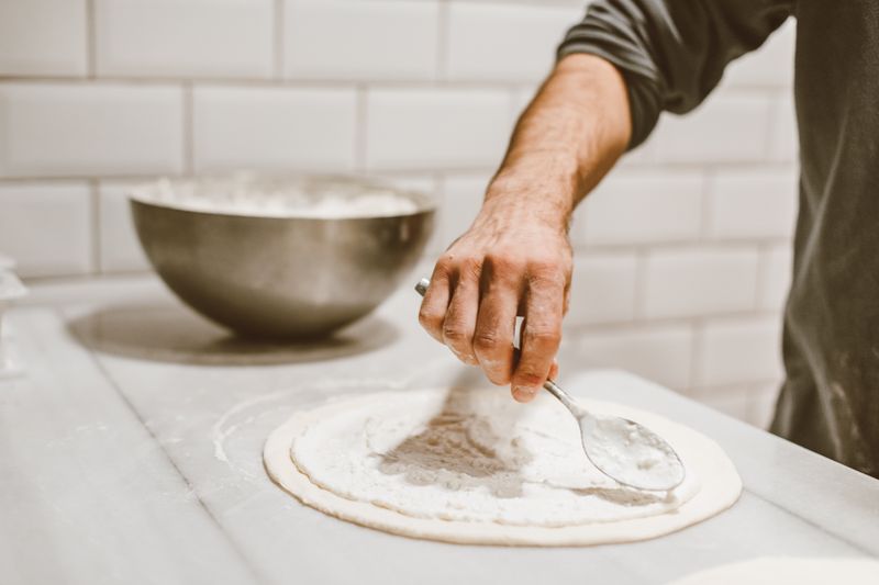 Round table pizza team preparing fresh ingredients with care